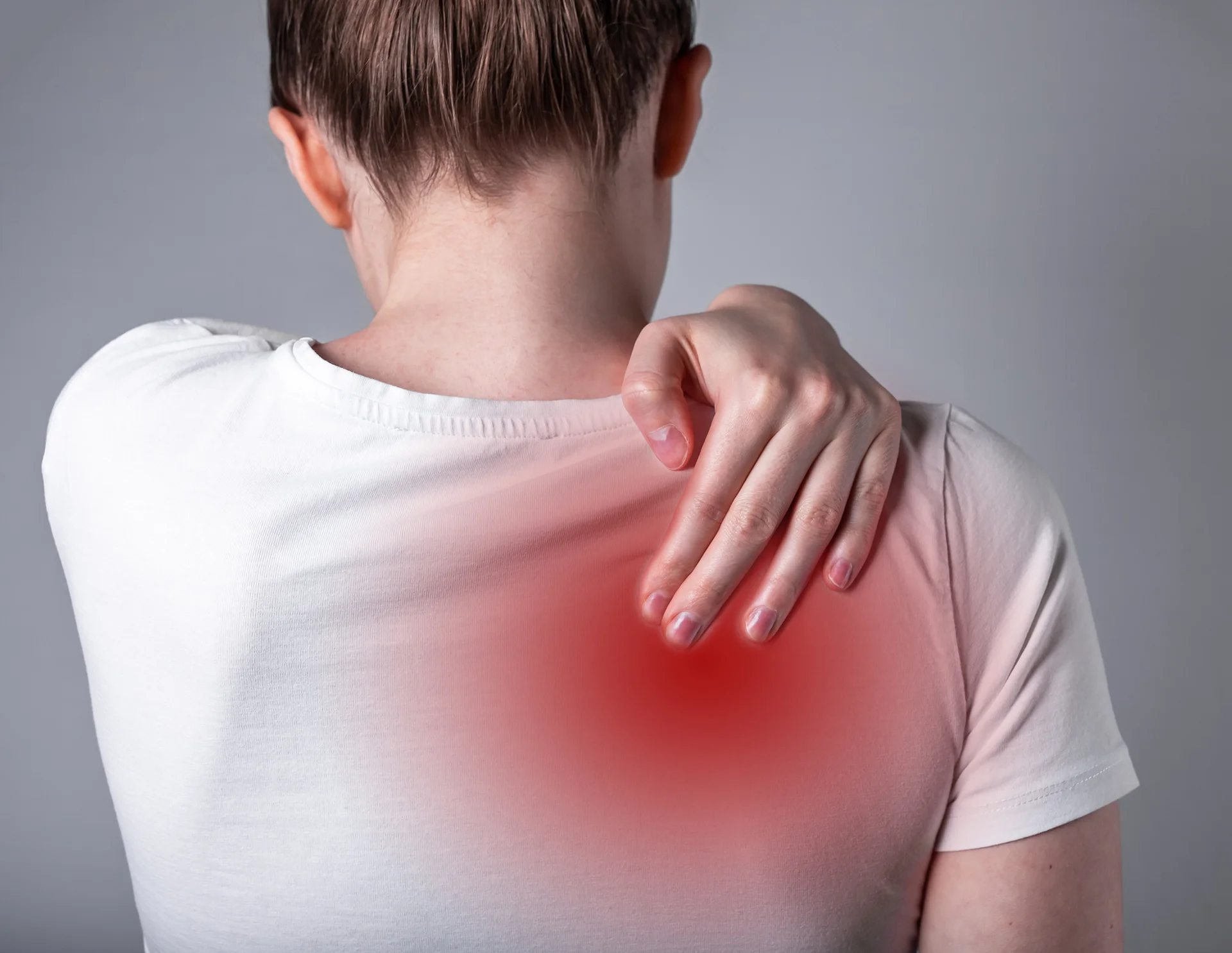 a woman suffers from back pain between shoulder blades
