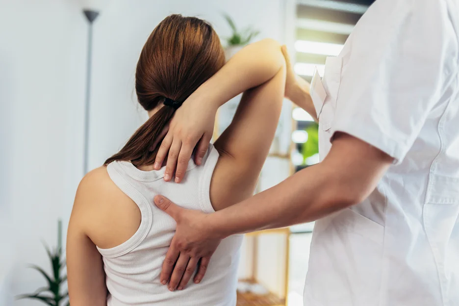a doctor examines the patient's back due to sciatica pain from scoliosis
